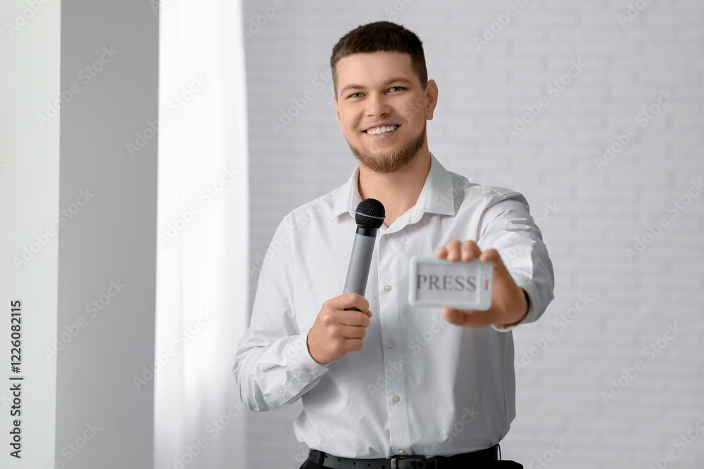 Male reporter with microphone and PRESS badge in office