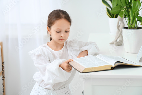 Cute little girl reading Bi...