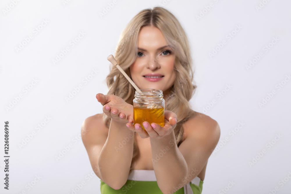 A Woman Gracefully Holding a Jar of Honey with a Dip Stick for Tasting and Serving A Woman Gracefully Holding a Jar of Honey with a Dip Stick for Tasting and Serving