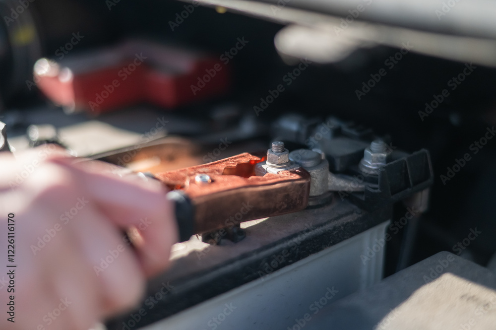 Woman holding clamps for charging a car battery. 