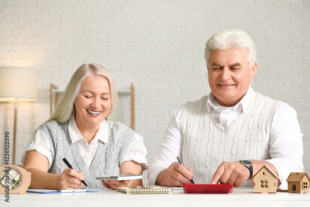 Senior couple calculating utility bills on table at home Senior couple calculating utility bills on table at home