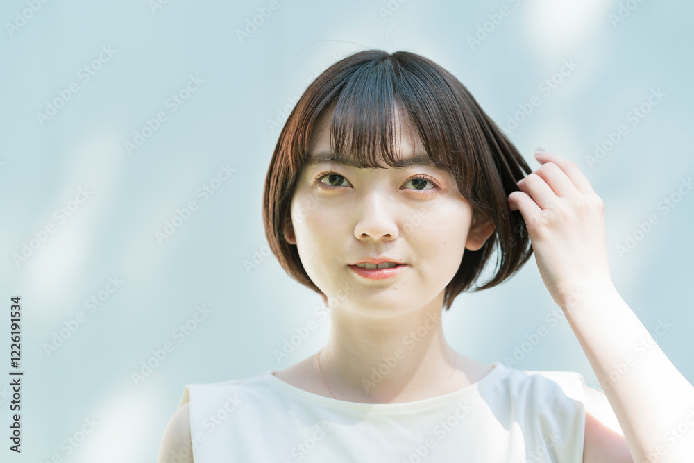 髪を整える女性と、白壁に映る木々の影 髪を整える女性と、白壁に映る木々の影