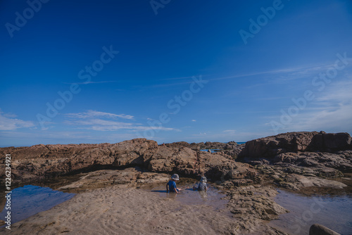 two children playing in rock pools 