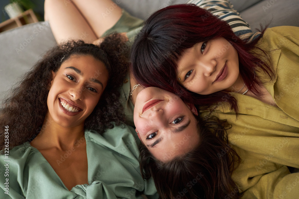 Fototapeta premium Close-up shot of three young ethnically diverse best friends posing for portrait while relaxing in living room