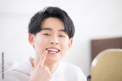カメラ目線で笑顔のホワイトニングや歯並び、歯の矯正のイメージ　若い20代男性クローズアップ photo
