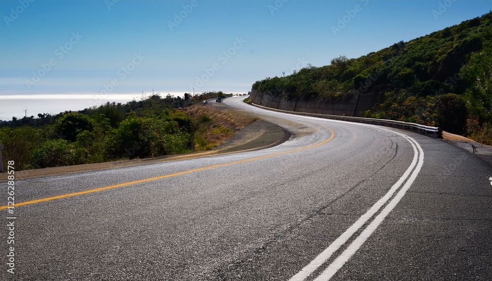 Curving coastal highway winds through lush green hills towards a distant ocean. Curving coastal highway winds through lush green hills towards a distant ocean.
