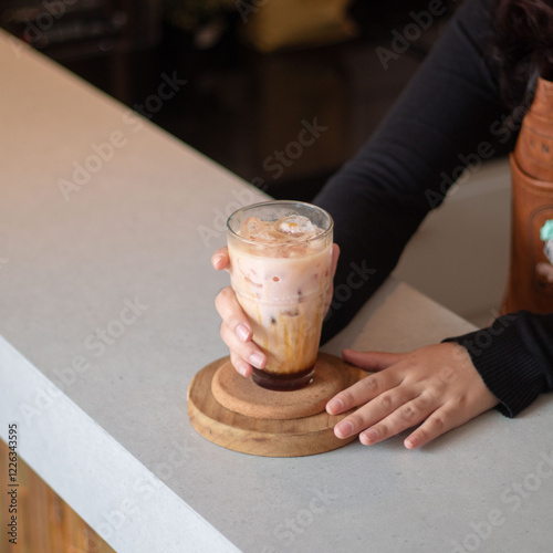 A person enjoys a creamy iced beverage at a stylish cafe, showcasing a blend of textures and flavors on a warm afternoon