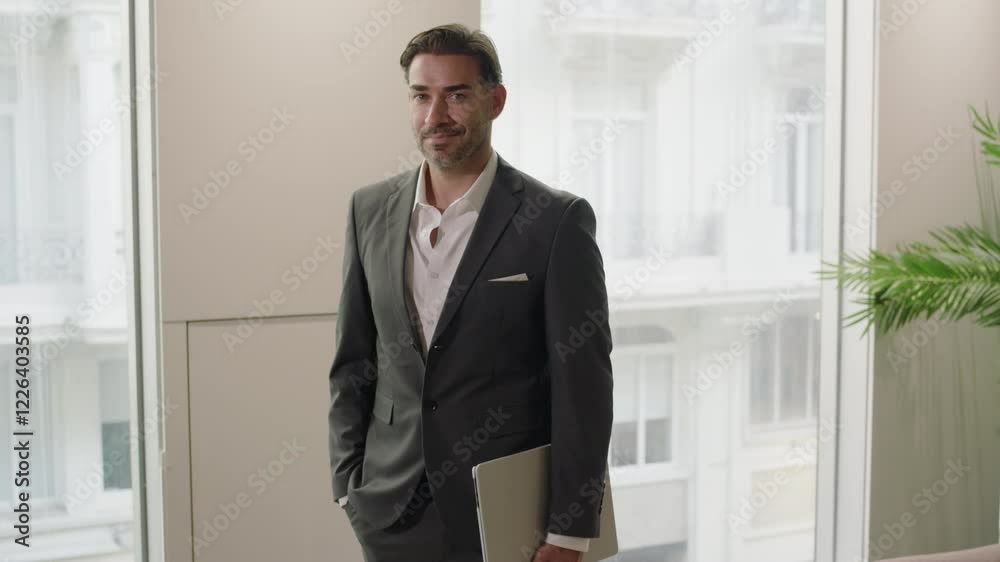 Poised and focused businessman stands confidently in a bright and modern office environment, fully embodying a busy and highly professional demeanor as an innovative software developer
