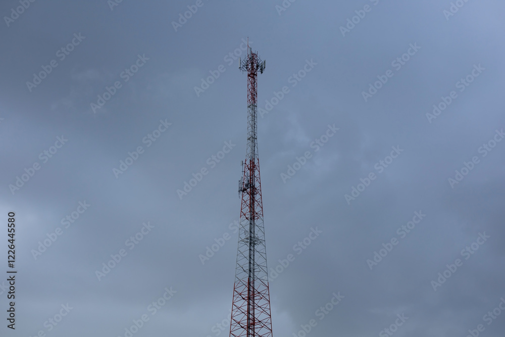 Red and white mobile phone signal tower on a cloudy day Red and white mobile phone signal tower on a cloudy day