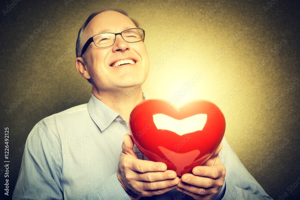 Sign of love and affection. Commercial digital ads visual idea. Adult valentine's day greeting card: midlife man with happy face holds red heart in hands. Couple walking in nature. Sign of love and affection. Commercial digital ads visual idea. Adult valentine's day greeting card: midlife man with happy face holds red heart in hands. Couple walking in nature.