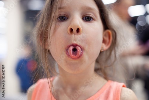 Girl rolling tongue into tube, close up. Articulation logopedic for mouth, speech therapy, tongue gymnastics concept. photo