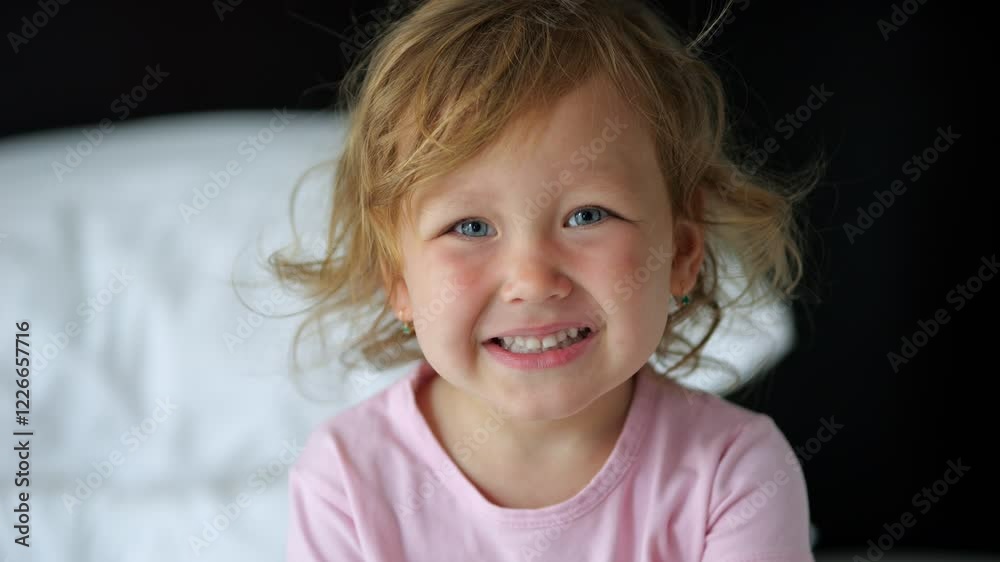 Shy little girl glances at camera with soft smile on youthful face Shy little girl glances at camera with soft smile on youthful face