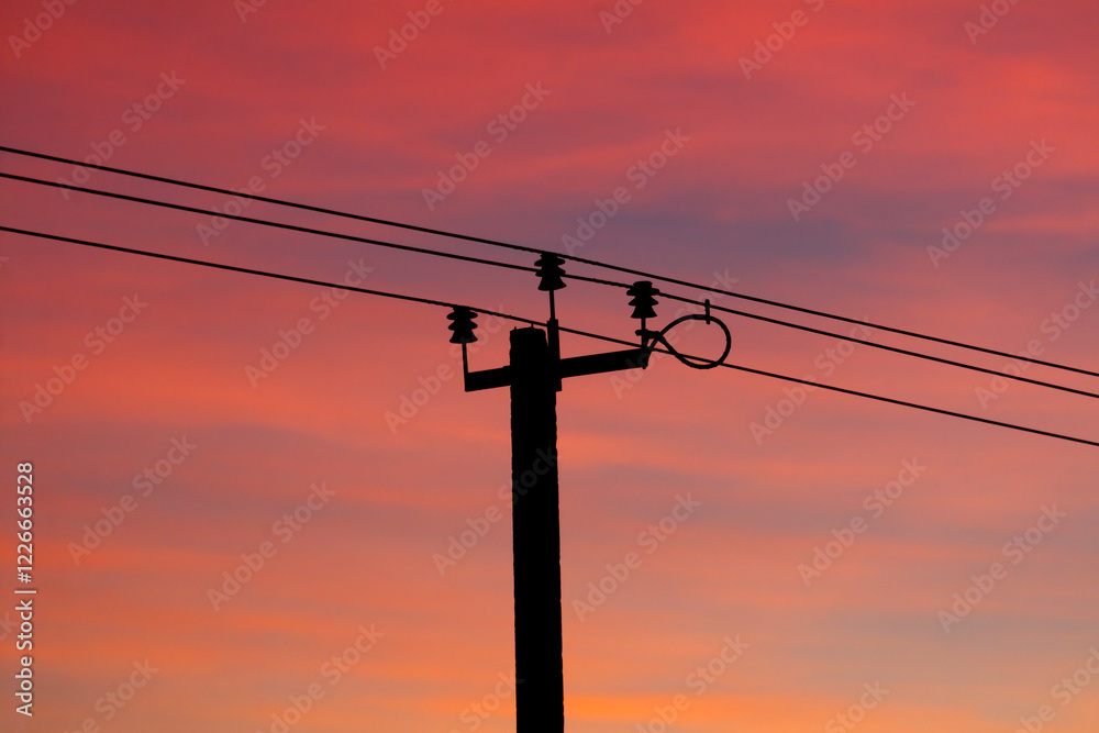 A power line pole is silhouetted against a beautiful sunset A power line pole is silhouetted against a beautiful sunset