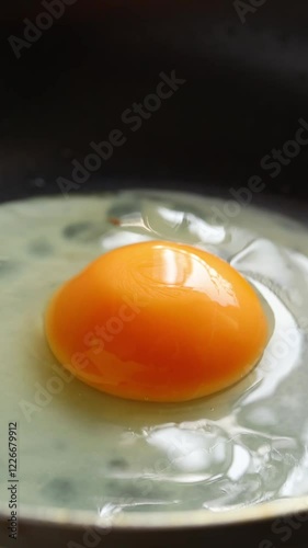 Cracked raw chicken egg into hot frying pan
