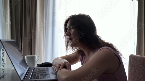 Young woman rests head on hands overwhelmed working on laptop