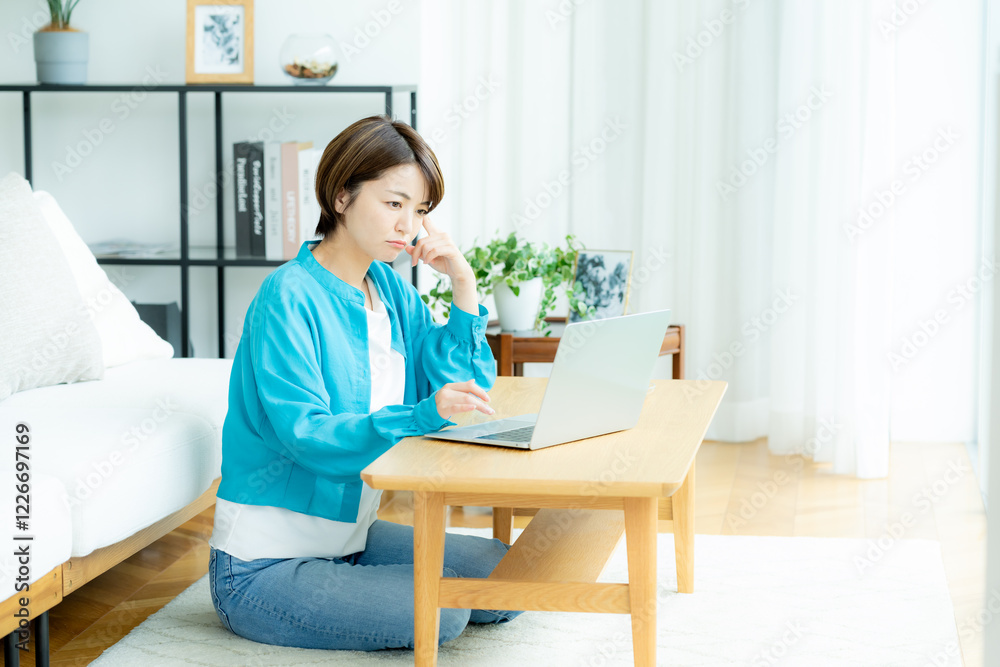 自宅でノートパソコンを操作する女性 自宅でノートパソコンを操作する女性