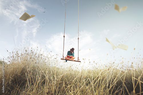 woman on a swing suspended in the sky reads a book, surrounded by flying pages that look like birds photo