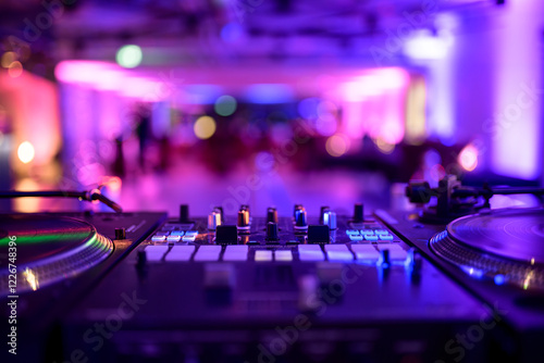 Close-up of a DJ turntable with vibrant party lighting and blurred background.