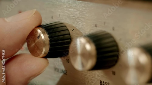 A man's finger presses the on off switch on a modern retro-style amplifier (portable loudspeaker) and adjusting the volume. Closeup. Macro. Shallow depth of field. Shot in motion