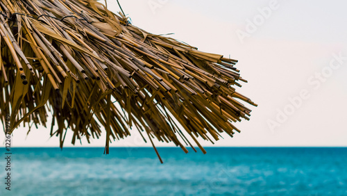 fragment of a straw beach umbrella against the background of the sea