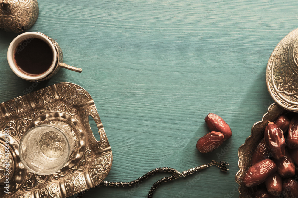 Bowl with date fruits, glass of water and cup of coffee on wooden table. Top view. Ramadan background. Toned image