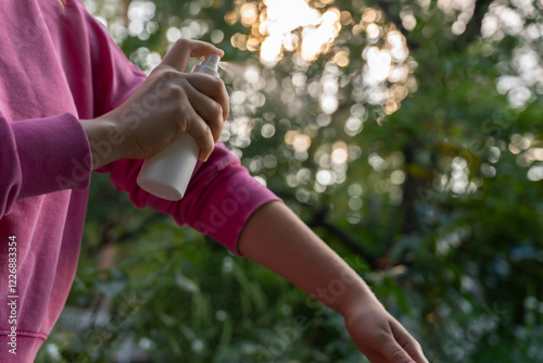 Hand applying insect repellent mosquito insecticide spray to kill flies bugs and mosquitoes on skin outside. Malaria zika virus and dengue fever prevention. Protective measures
