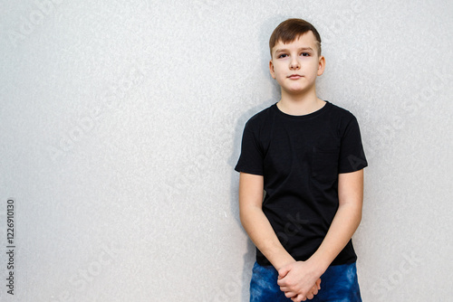 Portrait of a ten year old boy against a grey wall in a black T-shirt. photo