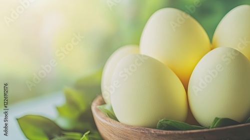 close-up of pastel yellow easter eggs placed in rustic wooden bowl surrounded by greenery and diffused light photo