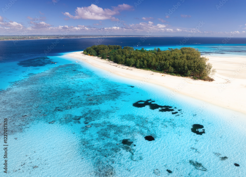 Obraz premium Aerial view of blue sea and amazing Mnemba island, Zanzibar. Top drone view of white sandy beach, boats, green palms, ocean with clear azure water in summer. Tropical background. Seascape. Travel