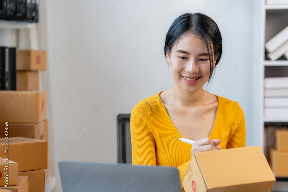 Smiling Woman Packing Order: A young, smiling woman in a yellow top efficiently packs an online order, surrounded by cardboard boxes in her home office. Smiling Woman Packing Order: A young, smiling woman in a yellow top efficiently packs an online order, surrounded by cardboard boxes in her home office.