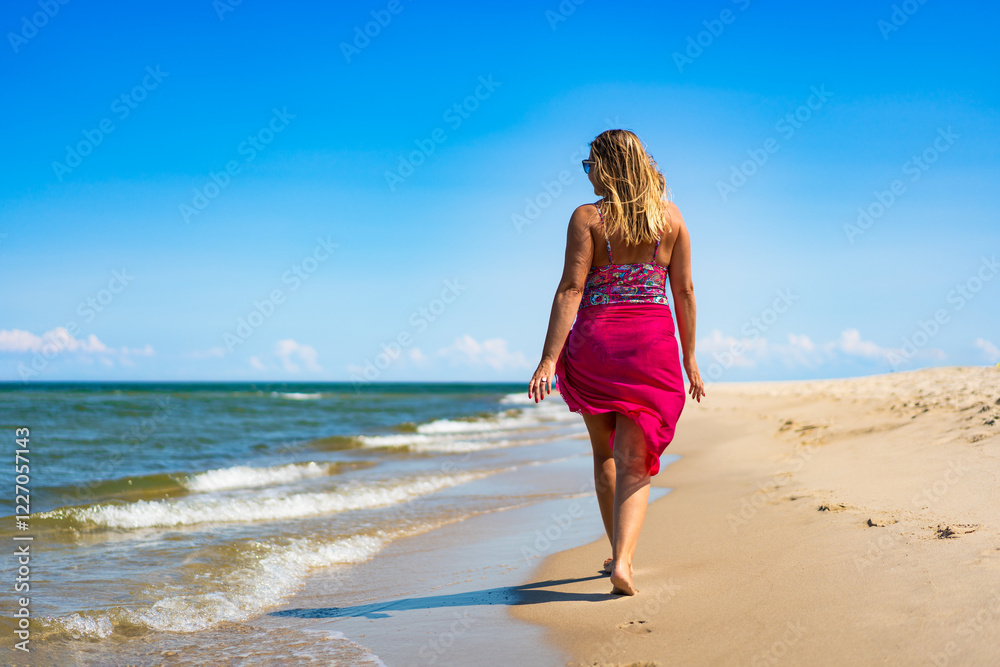 Beautiful middle aged woman tourist on beach holidays on sunny day. Back view Beautiful middle aged woman tourist on beach holidays on sunny day. Back view