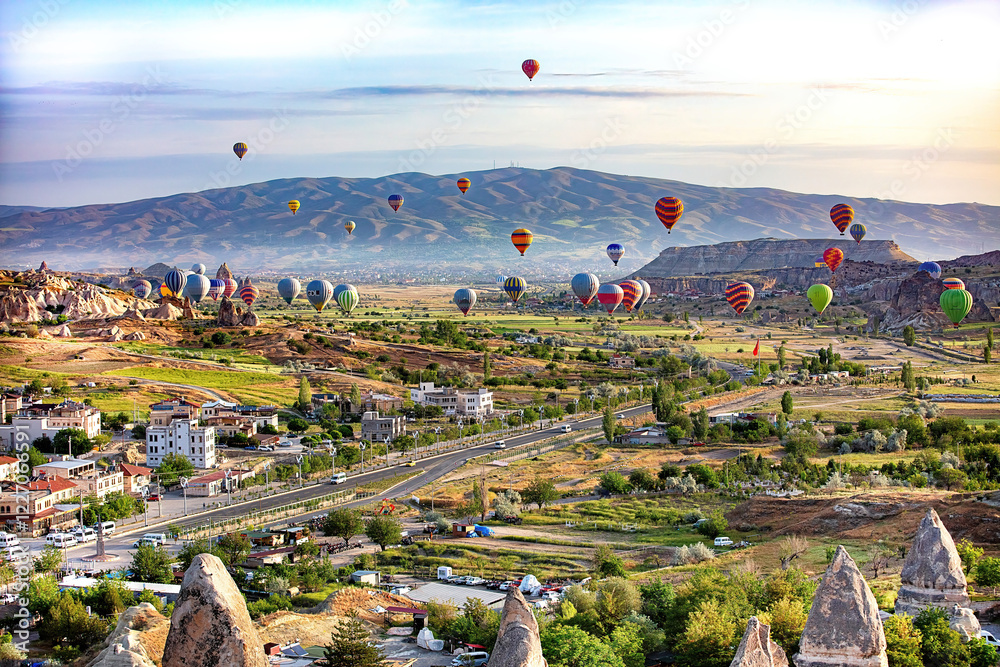 Colorful hot air balloons soar over stunning Cappadocia landscape at sunrise