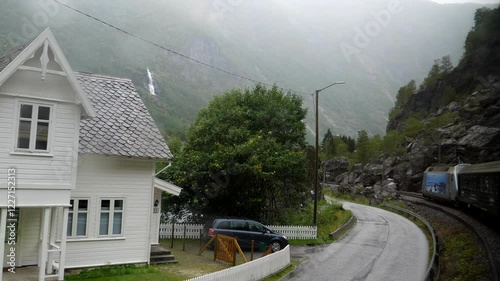 Train passenger POV of mountain river by winding road and railroad in the deep valley of Norwegian mountains between Myrdal and Flam village.