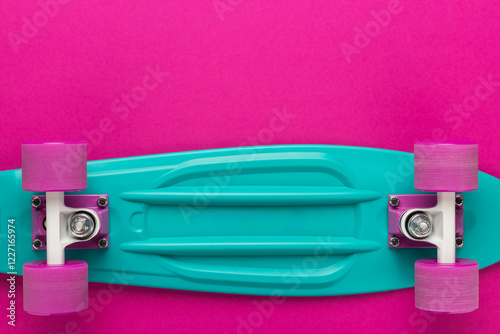 Photo of turned over children skateboard with copy space. Plastic mini cruiser board on deep pink with background. photo