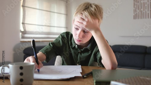 A teenage boy sits at his desk in his room, surrounded by books, notes and laptop, focusing on his studies	
