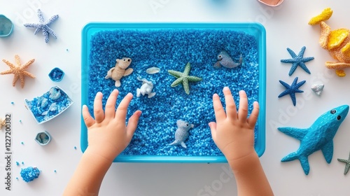 Child's hands exploring ocean-themed sensory bin with sea creatures and starfish