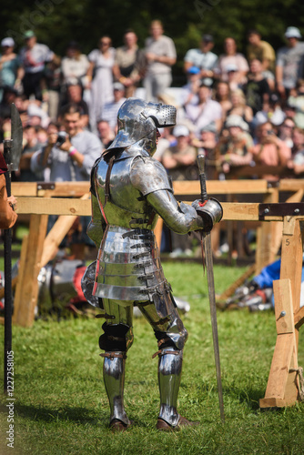 Knight Tournament Participant in Heavy Metal Armor Standing on Grass Field
