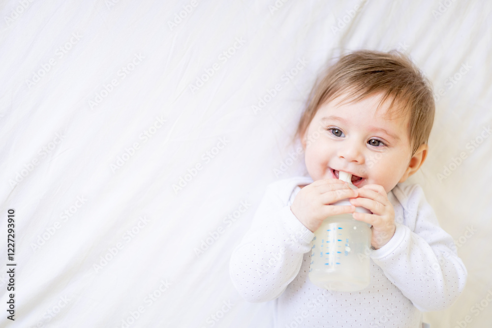baby sucking a bottle of milk on a white cotton bed at home, cute little baby girl eating milk, baby food concept, close-up portrait baby sucking a bottle of milk on a white cotton bed at home, cute little baby girl eating milk, baby food concept, close-up portrait