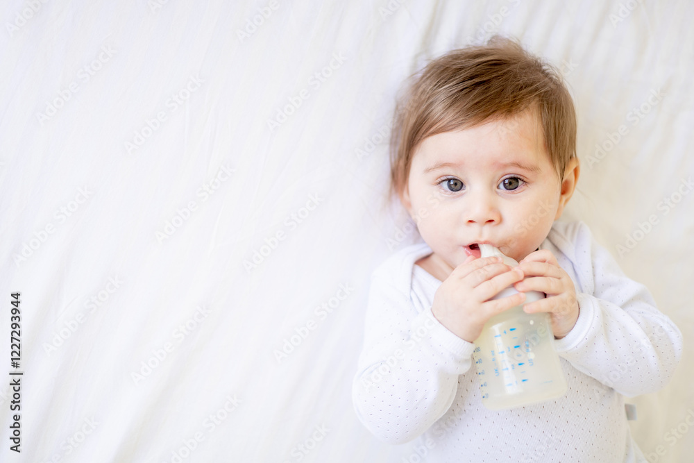 baby sucking a bottle of milk on a white cotton bed at home, cute little baby girl eating milk, baby food concept, close-up portrait baby sucking a bottle of milk on a white cotton bed at home, cute little baby girl eating milk, baby food concept, close-up portrait