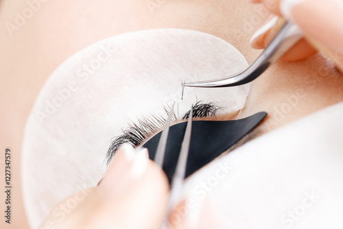 Eyelash extension procedure. Master tweezers fake long lashes beautiful female eyes