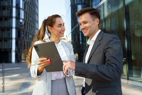 Professionals discussing ideas while using a tablet in a modern urban setting during daylight hours photo