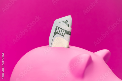 Fototapeta Naklejka Na Ścianę i Meble -  Close-up photo pink pig moneybox with dollars in it. Savings for retirement and personal finance concepts. One hundred dollar bill in pink piggy bank.