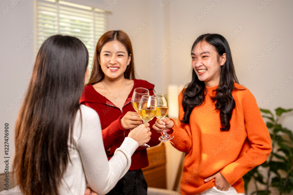 Three women are standing in a room, each holding a wine glass and smiling Three women are standing in a room, each holding a wine glass and smiling