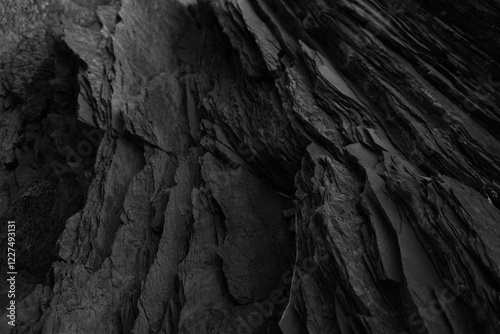 Black rock background. layered mountain surface close up. dark stone texture. cracked layers of slate