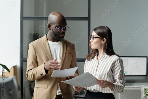 Young African American male broker and his female colleague looking at one another during discussion