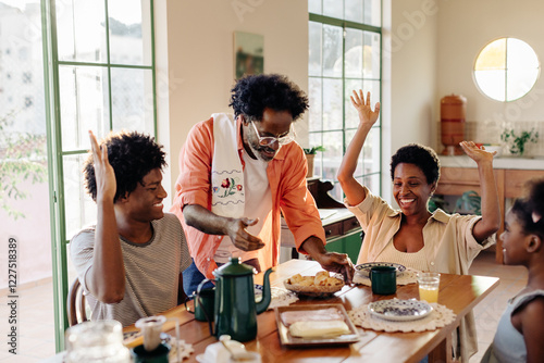 Family cheering with excitement as dad serves Brazilian cheese bread rolls at breakfast photo