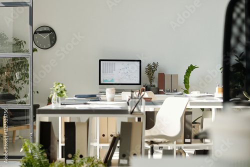 Workplaces of white collar worker with desktop computer, green plants, folders with documents and other supplies photo