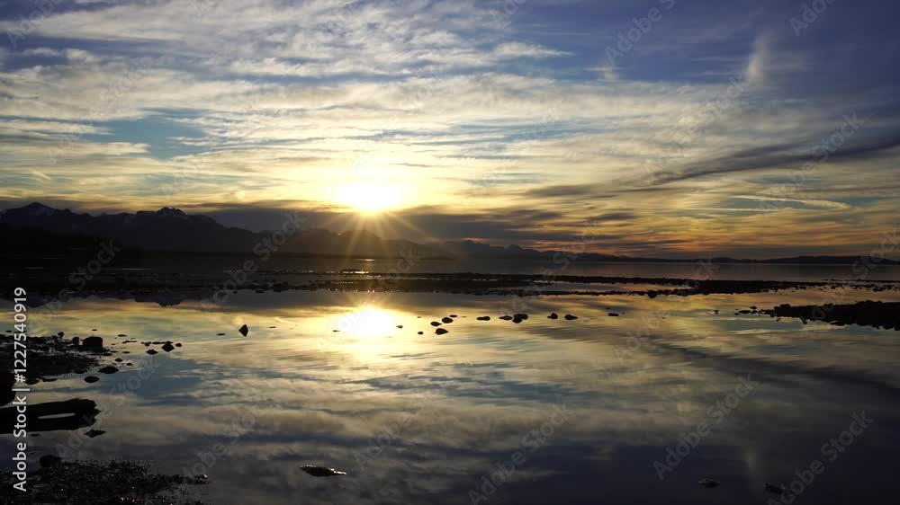 Sonnenuntergang über einem Bergpanorama an einem See mit Spiegelung im Wasser Sonnenuntergang über einem Bergpanorama an einem See mit Spiegelung im Wasser