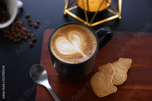 Hot Cappuccino coffee with black cup on old wooden table with isolate in black background