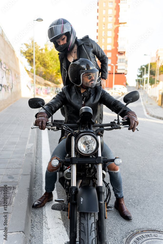 Fototapeta premium Bikers couple wearing protective helmets riding motorcycle in city street